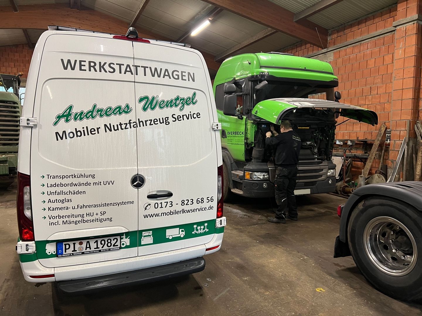 Die Rückansicht von einem weißen Sprinter und ein Mann bastelt an einem grünen Lkw